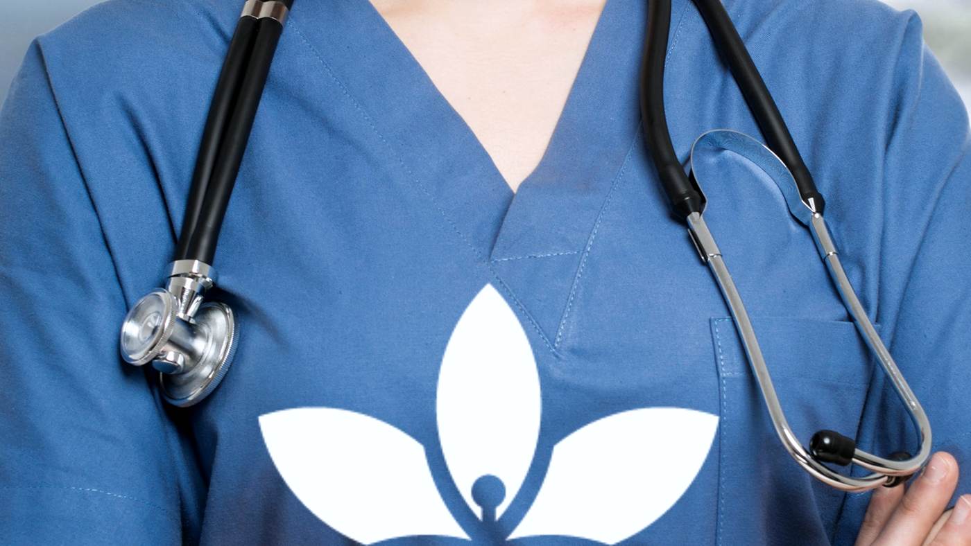 A West Guelph Medical Clinic team member in branded scrubs, the clinic logo on the tunic